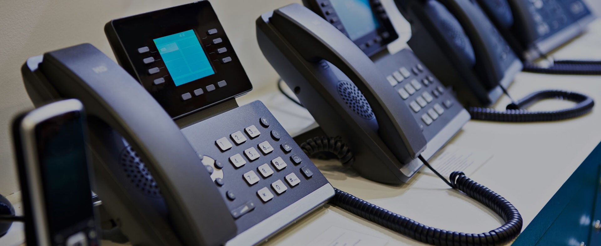 Row of enterprise VoIP desk phones with color displays deployed for broadcast media station communications